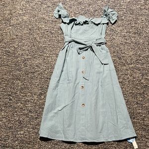 Off the shoulder light blue dress with brown buttons.